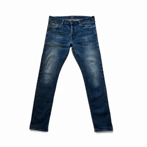 Mörkblå Scotch & Soda slim fit jeans, Storlek 33/34, Mycket bra skick - Mörkblå tvättade jeans från Scotch & Soda i snygg och tidlös design. Jeansen är använda en del men i väldigt bra skick och har mycket kvar att ge. Enda defekten är en liten brun fettfläck på höger lår, som knappt märks och syns mycket svagt på bild 7. Fläcken bedöms troligen försvinna efter 1–2 tvättar. Storlek 33/34. Hör gärna av dig om du vill ha fler bilder eller har frågor!