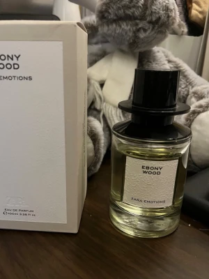 Zara Emotions Ebony Wood 100ml - Ebony Wood från Zara Emotions är en Eau de Parfum med en ursprunglig volym på 100 ml. Skick: Denna flaska är använd och jag uppskattar att det finns cirka 80-90 ml kvar. Den har förvarats mörkt och svalt, skyddad från solljus, vilket bevarat doftens kvalitet. Ebony Wood är en varm och kryddig med en ursprunglig. Doften är designad av Jo Malone och har en elegant profil, perfekt för dig som gillar träiga och mysiga dofter.