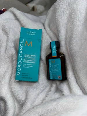 Moroccanoil Treatment 25 ml - Moroccanoil Treatment i en brun glasflaska med turkos etikett och svart lock. Kommer med matchande turkos förpackning. Innehåller 25 ml och är alkoholfri. Perfekt för alla hårtyper och ger glans och näring.