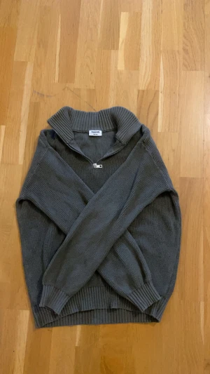 MörkGrön stickad tröja med half zip Kappahl - Mörkgrön stickad tröja från Kappahl med ribbad krage och half zip-dragkedja framtill. Tröjan har långärmade och breda muddar vid ärmslut och nederkant. Perfekt för kyliga dagar och enkel att matcha med jeans eller mjukis.