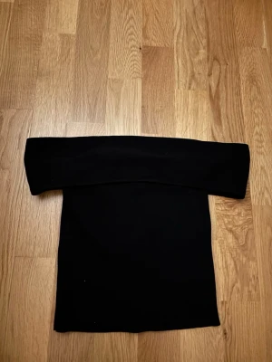 Svart offshoulder tubtopp - Säljer en stilren svart tubtopp med bred offshoulder-krage. Toppen har en enkel och clean design som är lätt att matcha med olika outfits. Perfekt för dig som gillar minimalistisk stil och vill ha något som sticker ut lite extra. Är från Gina tricot.