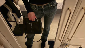 Svart axelväska med nitar från Maje - Svart axelväska från Maje i skinn med silverfärgade nitar framtill och fransar på sidorna. Väskan har både handtag och lång axelrem, perfekt för att bära crossbody. Stilren men med edgy detaljer som gör den unik, passar till alla tillfällen och outfits!❣️