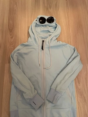 CP Company Zip Up Hoodie (Ljusblå) - En sparsamt använd CP Company Zip Up Hoodie i Ljusblå. Det är bara att hojta till om du har några frågor!