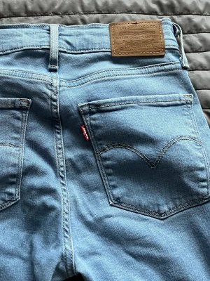 Levi's Premium 724 High Rise Straight jeans - Säljer ett par Levi's Premium 724 High Rise Straight jeans i ljusblå tvätt. Modellen har hög midja och raka ben som blir lite pösigare längst ner på benet, klassiska fem fickor och Levi's patch bak. Jeansen är gjorda i mjukt bomullsdenim och har snygga kontrastsömmar. Jeansen har lite slitage längst ner på benet men inget man ser om man inte tittar noga 