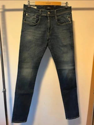 Replay mörkblå skinny jeans - Snygga mörkblå jeans från Replay med skinny passform och klassisk femficksdesign. Jeansen har slitningar och tvättade detaljer för en cool look, samt dragkedja och knapp framtill. Perfekta för dig som gillar stilrena och moderna jeans. Strl.  33/34