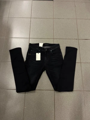 Svarta slimmade jeans från tiger of sweden W30 L32 - Svarta jeans från tiger of sweden med smal passform och smal fot. Klassisk femficksdesign, snyggt läderpatch bak i midjan och diskret tvättad look. Perfekt för dig som gillar en modern och slimmad stil.