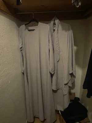 Beige abaya  - Säljer en stilren beige abaya med rund hals och långa ärmar. Klänningen har en enkel design och mjukt fallande tyg. Till klänningen ingår en matchande khimar.Perfekt för dig som gillar minimalistisk stil.