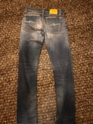 Blå jeans från Nudie - Feta nudie jeans i modellen grim tim. Skicket är 9/10 och originalpris runt 1500kr. Storlek 28:32. Hör av dig vid funderingar!