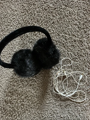 Svart fluffig öronvärmare i fuskpäls - Säljer en svart öronvärmare med supermjuk och fluffig fuskpäls. Perfekt accessoar för kalla dagar och ger en cool vinterlook. Bågen är täckt i samma mjuka material för extra komfort.