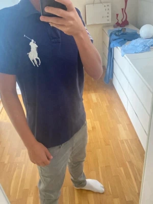 Mörkblå piké från Ralph Lauren Wimbledon - Säljer en mörkblå pikétröja från Ralph Lauren med stor vit polo- märke på bröstet och Wimbledon-märke på ärmen. Klassisk krage och korta ärmar, custom fit. Perfekt för dig som gillar tennis och snygga detaljer.