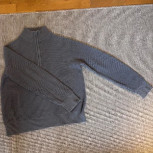 Grå stickad half zip-tröja från Grunt - Säljer en grå stickad tröja från Grunt i storlek M i BARN storlek (10-12). Tröjan har hög krage och half zip-dragkedja framtill. Den är ribbstickad och har långa ärmar, perfekt för kyliga dagar. Enkel och stilren design som funkar till det mesta.