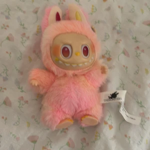 Rosa och gul lafufu - Söt Pop Mart The Monsters plyschfigur i rosa, med nyckelringsfäste. Perfekt som samlarobjekt eller accessoar. Mjukt material, fina färger och detaljer. Ser ut att vara i mycket gott skick utan synligt slitage eller defekter.