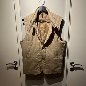 Beige quiltad väst från J.Lindeberg - Säljer en stilren beige quiltad väst från J.Lindeberg i storlek M och passar M. Säljer pga den ej passade. Nypris 1500kr och är i väldigt bra skick. Skriv gärna ifall frågor eller mer bilder! Pris kan diskuteras ifall snabb affär.