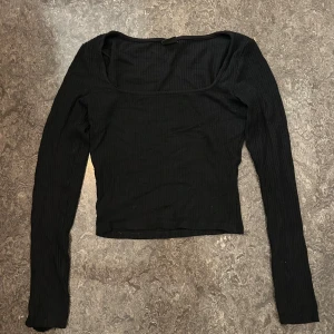 Svart Gina Tricot topp  - Svart långärmad topp från Gina Tricot i storlek XS. Toppen har en urringning och är cropped.