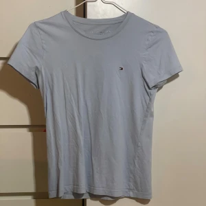Ljusblå t-shirt från Tommy Hilfiger - En stilren ljusblå t-shirt från Tommy Hilfiger med liten broderad logga på bröstet. Passar påse tjejer och killar. Kommer ej till användning. Pris kan diskuteras💞
