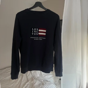 Navy Lexington sweatshirt - Navy sweatshirt från Lexington med broderad logga och flagga framtill. Perfekt för en chill och stilren look.