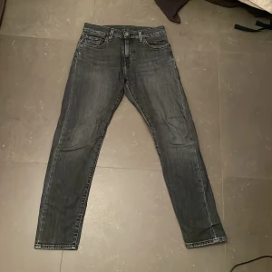 Levi's 512 svarta jeans - Säljer ett par svarta Levi's 512 jeans med snygg tvättad look och klassiska fem fickor. Jeansen har en slim passform med rakare ben och är tillverkade i mjukt denimtyg. Perfekta för dig som gillar stilrena och bekväma jeans.