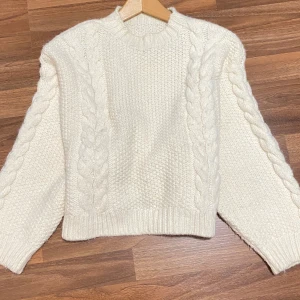 Beige stickad tröja med flätmönster - Supermysig cremevit stickad tröja med grovt flätmönster längs ärmar och fram. Är inte helt säker på vart den är köpt och storlek men tror H&M storlek S/M