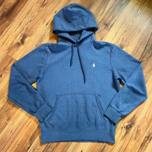 Blå hoodie från Polo Ralph Lauren - Blå Ralph lauren hoodie storlek S                        - längd (63cm), bredd (49cm), ärm (60cm)            - 8/10 skick, inga defekter direkt, tappat lite färg bara                                                               Pris går att diskutera 🫡