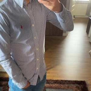 Randig blå skjorta Polo Ralph Lauren - Slim fit skjorta från Polo Ralph Lauren. Perfekt för dig som gillar stilren och fräsch look. Jag är 178 och väger 80kg. Skriv frågor vid funderingar