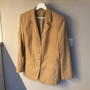 Beige/brun kavaj med Fendi inspiration - En jättefin Fendi inspirerad kavaj i storlek 44, köpt på weekday secondhand i Stockholm.