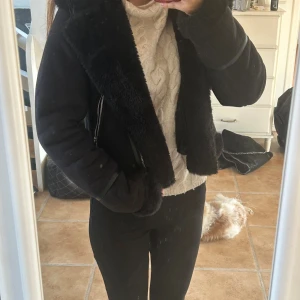 Svart pälsjacka från Pull&Bear XS - Snygg svart pälsjacka från Pull&Bear i storlek XS. Jackan har mjuk fuskpäls på insidan och kragen, dragkedja i sned modell och detaljer i skinnimitation på ärmarna. 