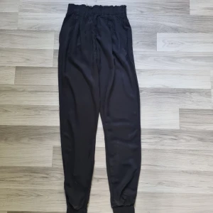 Svarta byxor från BikBok XS - Svarta byxor från BikBok i storlek XS. Byxorna har hög midja med resår och avslappnad passform, samt muddar vid bensluten. Perfekta för en chill och bekväm stil.