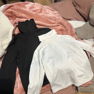 Svart och vit polotröja i bomull - Två stilrena polotröjor i svart och vitt med hög krage och långa ärmar. Snyggt basic-plagg för garderoben.