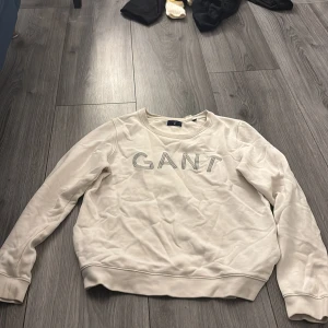 Vit sweatshirt från GANT i bomull - Säljer en stilren vit sweatshirt från GANT i storlek M. Tröjan har rund halsringning, långa ärmar och GANT-logga broderad framtill. Tillverkad i mjuk bomull och passar perfekt till jeans eller mjukisbyxor.
