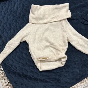 Beige stickad polotröja från H&M - Säljer en beige stickad polotröja från H&M i storlek XS. Tröjan har en bred polokrage, långärmade ärmar och ribbade muddar vid ärmslut och nederkant. Perfekt för kyliga dagar och enkel att matcha med jeans eller kjol.
