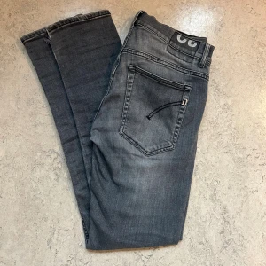 Gråa Dondup jeans - Säljer ett par grå jeans från Dondup i storlek 32. Jeansen har en snygg tvättad look, klassiska fem fickor och raka ben. Materialet är mjukt jeans och bakfickorna har Dondup-logga. Perfekta för dig som gillar stilrena och bekväma jeans.