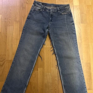 Blå jeans med råa detaljer från Zara - Unika blå jeans från Zara med raka ben och coola råa kanter. Snygga vita sömmar som kontrast och slitna detaljer längs benen och bakfickorna. Klassisk femficksmodell i denim med normal passform. Perfekta för dig som gillar en edgy streetstil.