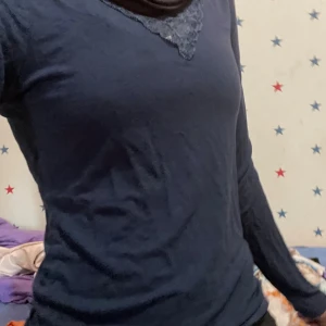 Mörkblå långärmad tröja med spets - Mörkblå långärmad tröja med v-ringning och dekorativ spetsdetalj vid halsen. Tröjan har en enkel och stilren design som passar perfekt till jeans eller kjol. Mjuk och skön att bära. Har använt den fem gånger. Storleken är 158/164, passar dig som har s/xs