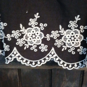 Svart linnetopp med broderade blommor - Svart linnetopp från Divided med tunna axelband som knyts. Nedtill finns vita broderade blommor och vågig kant. Toppen är ärmlös och har en söt, feminin stil som passar perfekt till sommaren.