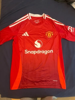 Manchester United adidas matchtröja S - Säljer en röd Manchester United matchtröja från adidas i storlek S, slim fit. Tröjan har vita detaljer, klubbmärke på bröstet och Snapdragon-logga framtill. Tillverkad i lätt polyester 