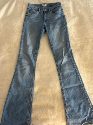 Bootcut jeans från ONLY i ljusblå denim - Snygga bootcut jeans från ONLY i ljusblå denim. Jeansen har en bootcut passform och är tillverkade i bomullsmaterial med lite stretch. Storlek small. Längd 34. Använda få gånger!