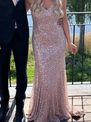 Champagnerosa glittrig balklänning - Supersnygg balklänning i champagnefärg med glittriga paljetter. Klänningen har v-ringning, smala axelband och figurnära passform som faller snyggt mot kroppen. Perfekt för bal eller student! Materialet känns lyxigt och skimrar i solen. Köpt på asos, mer info och bilder i dm 🩷