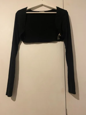 Svart bolerotopp med lång ärm - Säljer en svart topp med långärmad i storlek L. Den har en mjuk och stretchigt material från Cubus.