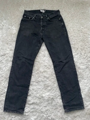 Svarta jeans från 157, W28 L32 - Svarta jeans från 157 med klassisk femficksdesign och raka ben. Jeansen har knapp och dragkedja framtill samt bälteshällor. Materialet är robust denim som ger en cool och tidlös look. Perfekt för dig som gillar enkel och stilren streetwear.