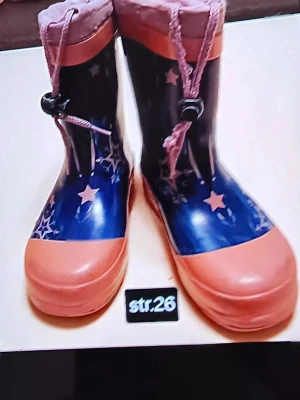 Blå och rosa gummistövlar med stjärnor - Färgglada gummistövlar i blått och rosa med stjärnmönster och dragsko upptill. Perfekta för regniga dagar och lek utomhus. Tillverkade i syntetmaterial och har rund tå samt platt sula.