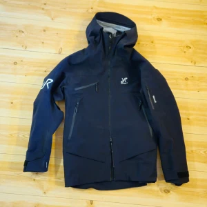 Helt Ny Revolution Race skal/skidjacka - Säljer en helt ny RevolutionRace HyperShell Pro skal-/skidjacka. Jackan är oanvänd och endast uppackad för bilder.  Vind- och vattentät skaljacka med bra  andningsförmåga. Funkar utmärkt för skidåkning, friluftsliv och som skaljacka året runt. Har huva, flera fickor, ventilation och snölås.  Säljs då den inte kommit till användning. Kan skickas mot frakt eller mötas upp runt om Lund/ Malmö.  Hör av dig vid frågor