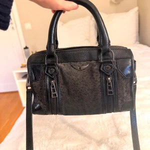 Svart handväska från Zadig & Voltaire modell sunny - Cool svart handväska i skinn från Zadig & Voltaire med subtilt leopardmönster. Väskan har två rejäla handtag, avtagbar axelrem med broderad logga, silverfärgade dragkedjor och detaljer. 💓 Nypris ca 5000 och modellen säljs inte längre 🩷