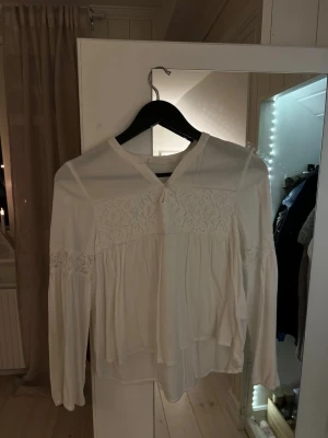 Vit blus från Kappahl  - Säljer en vit blus med blom broderier på bröstet och över armarna från Kappahl barn. 
