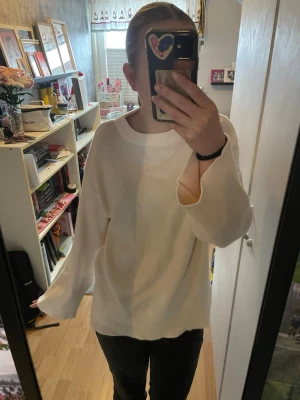 Vit oversized stickad tröja - Säljer en vit oversized stickad tröja med rund halsringning och breda muddar vid ärmslut och nederkant. Tröjan har en enkel och clean look, perfekt att slänga på sig när det är lite kyligt ute.