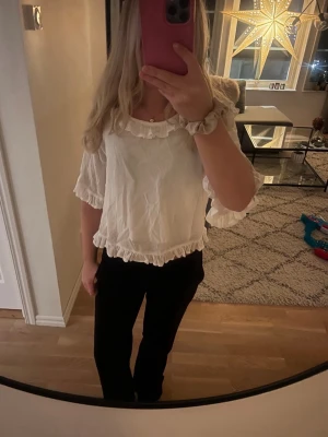 Vit blus med volangdetaljer - Säljer en söt vit blus med volangkant vid halsringning, ärmslut och nederkant. Blusen har en lös passform och trekvartsärm. Barnstorlek men passar xs/s💕💕Prislapp kvar tror jag