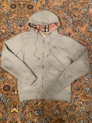 Grå Burberry Hoodie - Säljer en tvär fet grå burberry zip-up. Storleken stor M men den sitter som S. Den är rätt så kort men för mig passade den perfekt 🤩