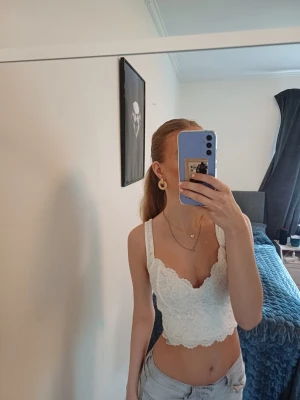Vit spetsig croppad linnetopp - Säljer en superfin vit croppad linnetopp med breda axelband och v-ringning. Toppen är täckt av spetsdetaljer och har en feminin, romantisk look. Perfekt till sommaren ❤️