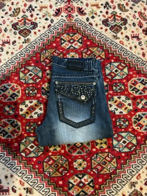 Redemtion jeans - Jeans med snygg tvätt och coola bakfickor ifrån märket redemption. Fickorna är i skinn material, vet ej om det är äkta eller inte. Jeansen är i jättebra skick använt fåtal gånger. Mått: 39 cm midja. 105 cm längd. 21,5 cm benöppning