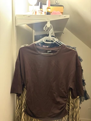 Brun topp med rynkade detaljer Gina Tricot - Säljer en brun topp från Gina Tricot i storlek M. Toppen har korta ärmar och cool rynkning på sidan som ger en snygg effekt. Materialet är mjuk bomull och modellen är normal passning. Perfekt att styla med jeans eller kjol! Inte använt alls mkt.