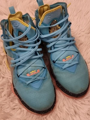 Nike LeBron 19 - Säljer ett par riktigt färgstarka Nike LeBron sneakers i blått med gula och rosa detaljer. Använd skick men varsamt använda.